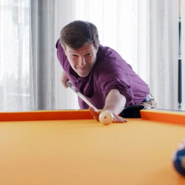 A man playing pool at Uplift Recovery Center