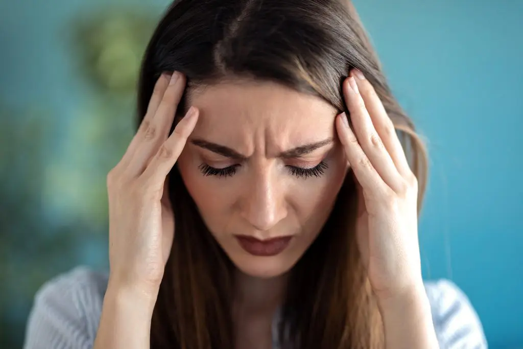 a young woman with her hands on her head experiencing physical relapse from addiction