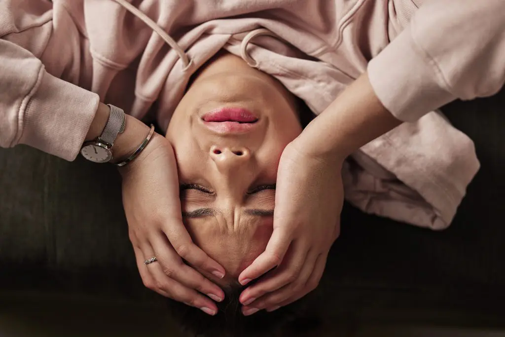 a woman lying down with her hands on her head, suffering from post acute withdrawal syndrome