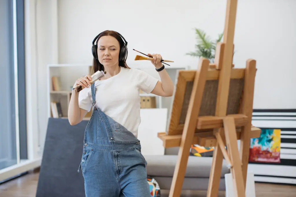 a woman painting as she listens to music during Anti-Boredom Month