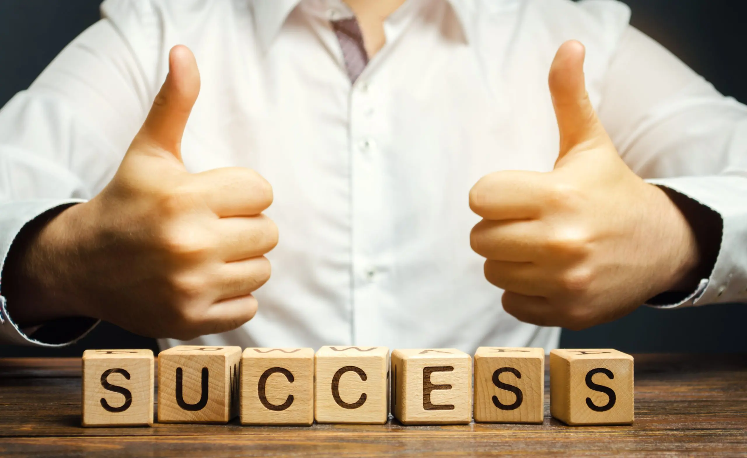 wooden blocks that spell "success" with a thumbs up in the background emphasizing the importance of Self-Improvement Month