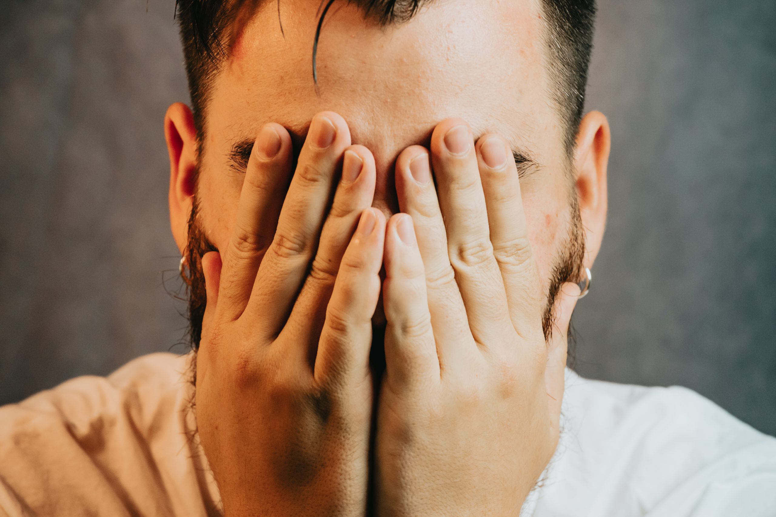 a man with his face in his hands as he is suffering from the medicating definition in recovery